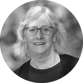 Person with white hair and glasses smiling