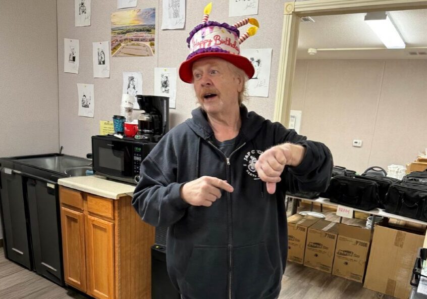 Man in birthday hat pointing at wristwatch