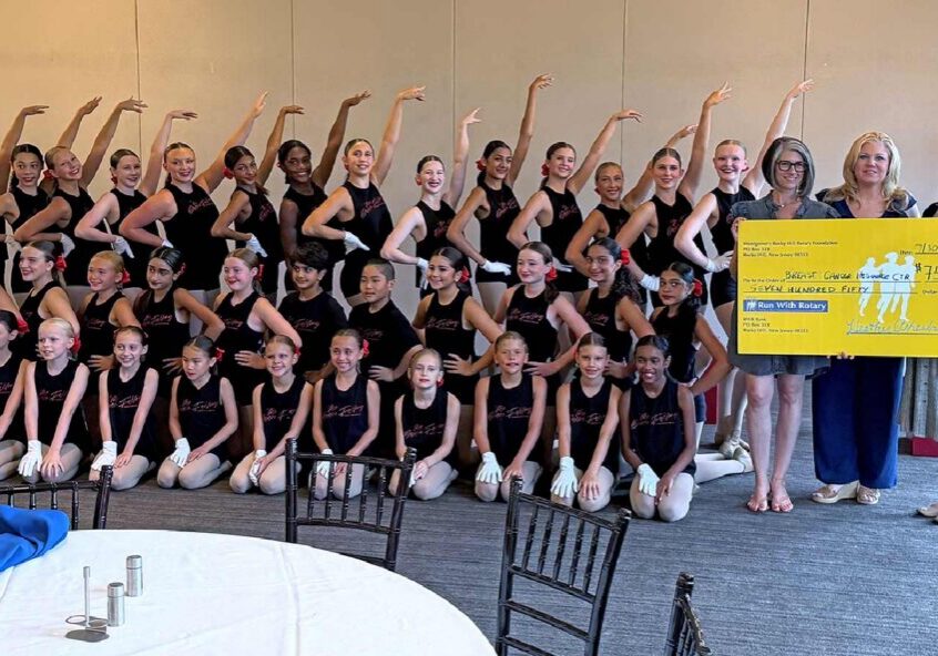 Dance troupe posing with oversized donation check