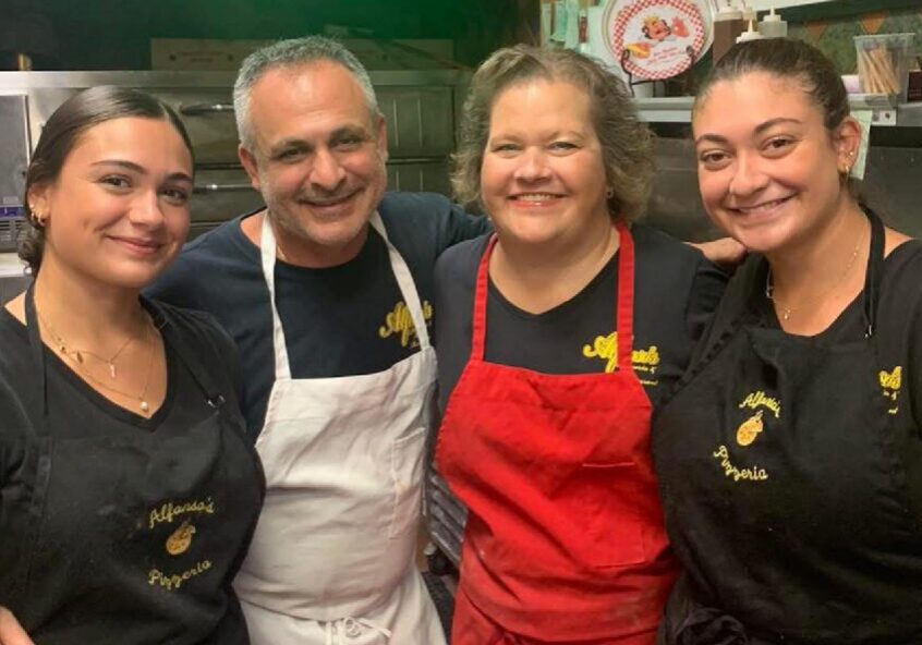 Four smiling kitchen staff wearing aprons