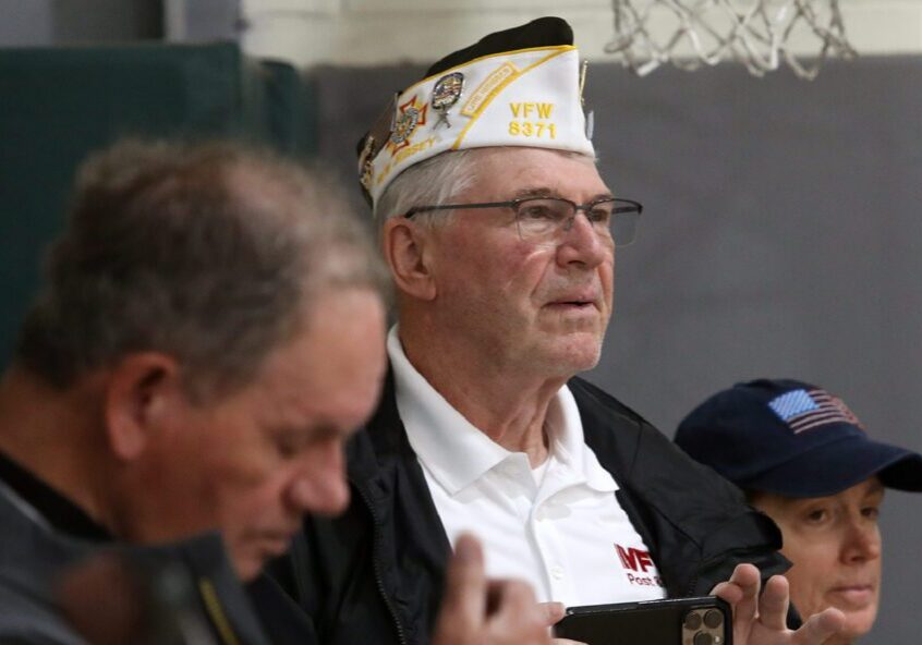 Veteran wearing VFW cap watches indoor event