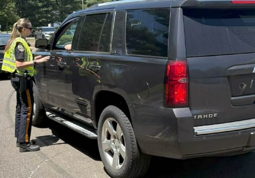 Officer checking driver through dark gray SUV window